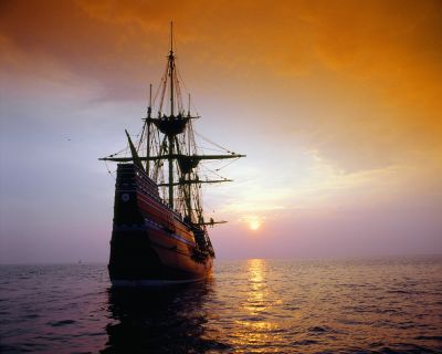 A photo of a 1600s ship sailing into the sunset.