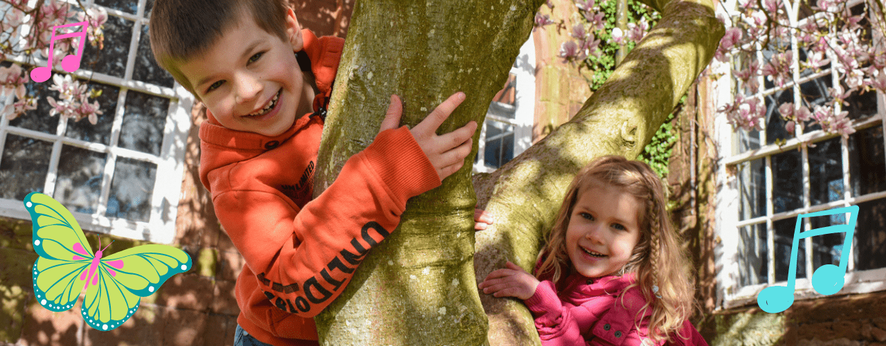 A girl and boy happily climbing in a tree.