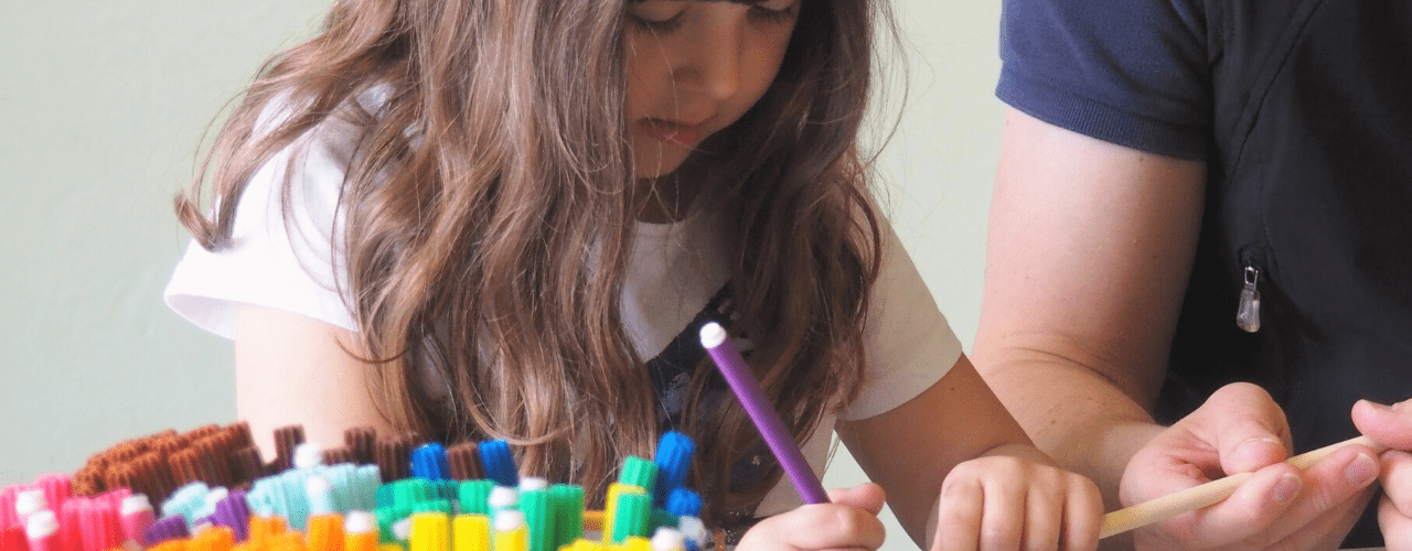 A girl concentrates as she draws on a wooden dowel.