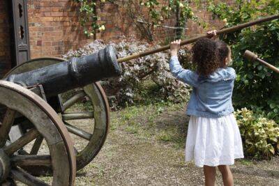 A photo of a child in The Commandery's garden; she is using a ramrod.