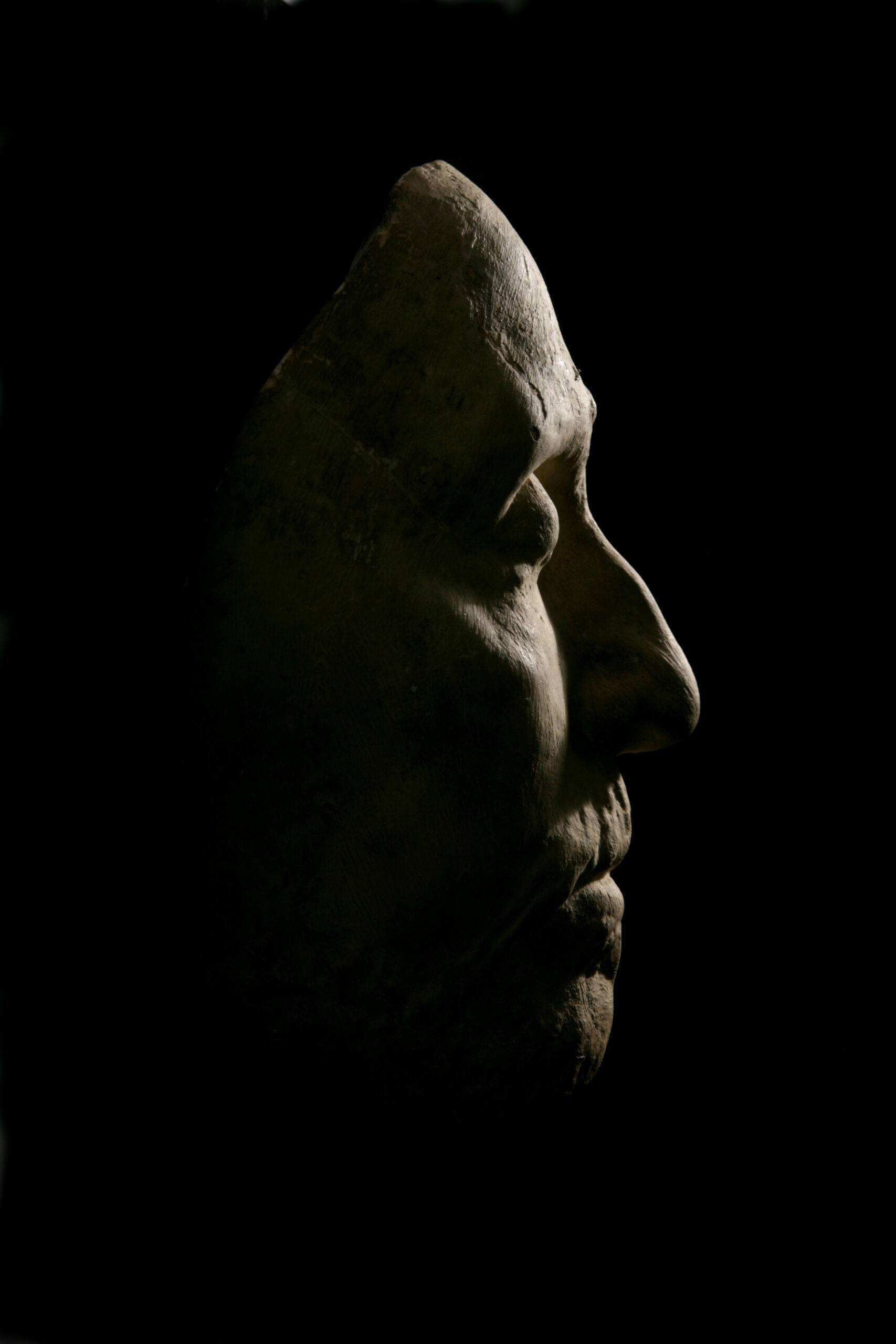 A photo of Oliver Cromwell's death mask, dramatically lit on a dark background.