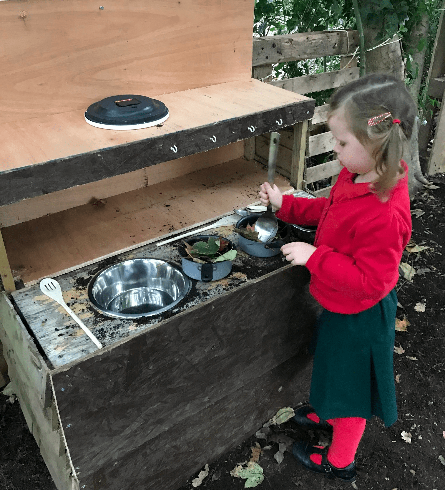 A photo taken in the mud kitchen showing a child playing - one of the things to do in the Nature Play Area.