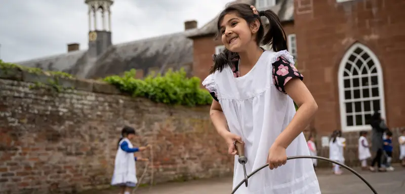 A photo showing a girl playing with a Victorian hoop outside Hartlebury Castle.