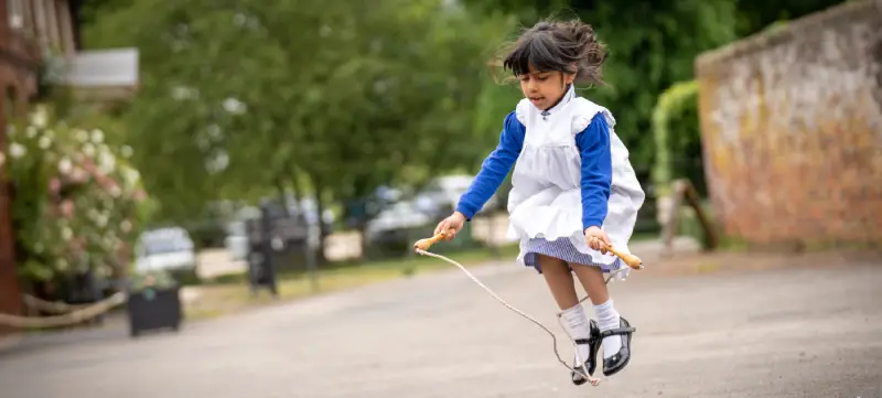 A girl skipping outside Hartlebury Castle; she is dressed as a Victorian schoolgirl.