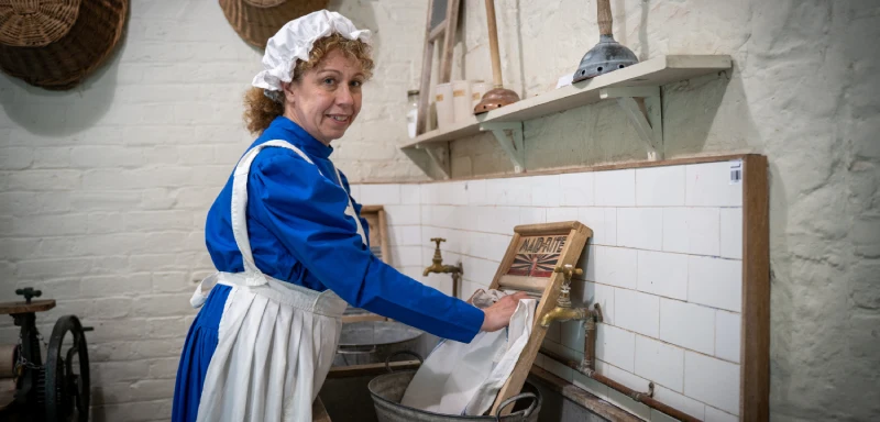 A woman dressed as a Victorian servant demonstrating laundry.