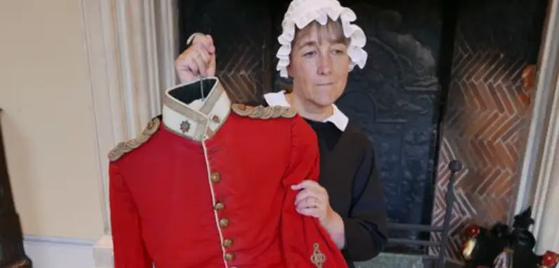 A photo showing a woman dressed as Florence Nightingale holding up a soldier's uniform.